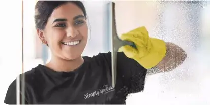 A Simply Spotless cleaning wiping down shower glass during a home cleaning service in Sydney