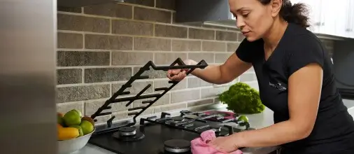 Simply Spotless employee cleaning a kitchen hob during a home cleaning service