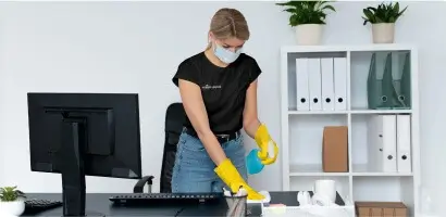 Simply Spotless employee cleaning a desk space during an office cleaning service